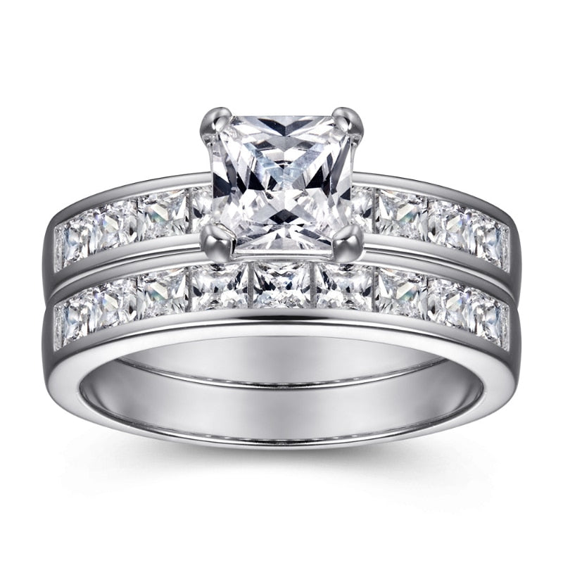 A silver ring set with small princess cut zircons, channel set in the shank and a princess cut moissanite set as the main gem. This ring is paired with a matching wedding band.
