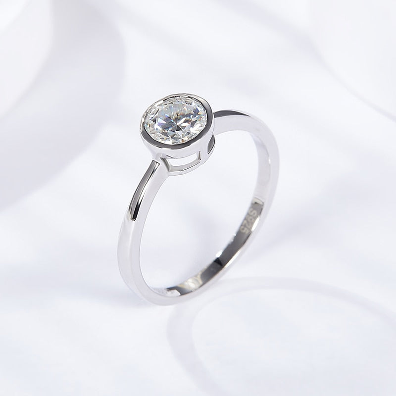 A silver round cut bezel set ring.