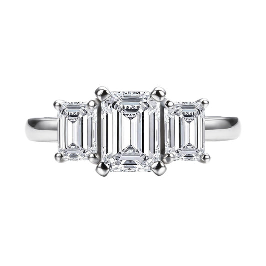 A silver 3 stone ring with a 1CT emerald cut moissanite set between two smaller emerald cut moissanites.