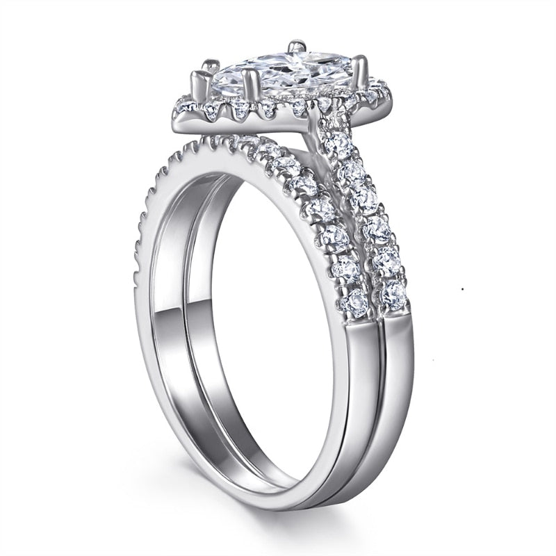 A silver pear cut moissanite halo ring with a matching pave wedding ring.