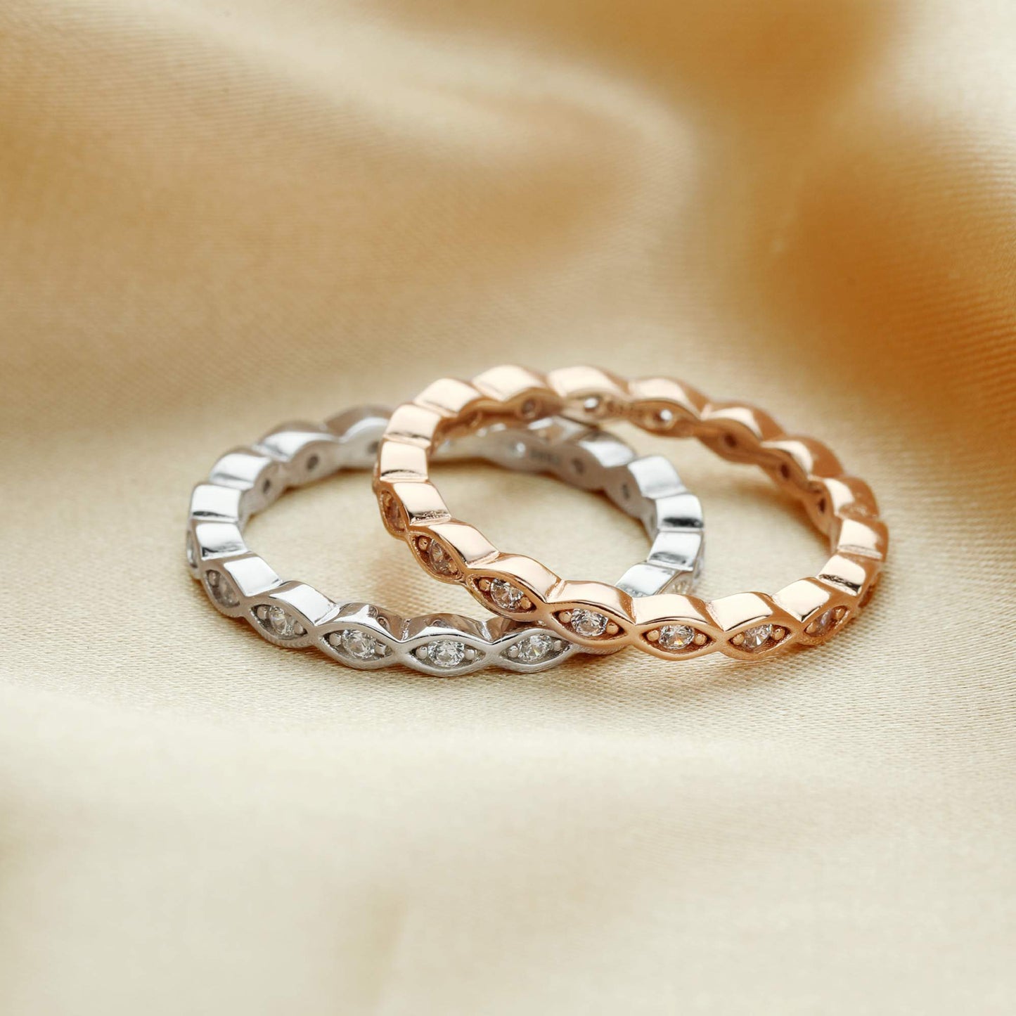 One silver and one rose gold scalloped ring band set with small clear stones.
