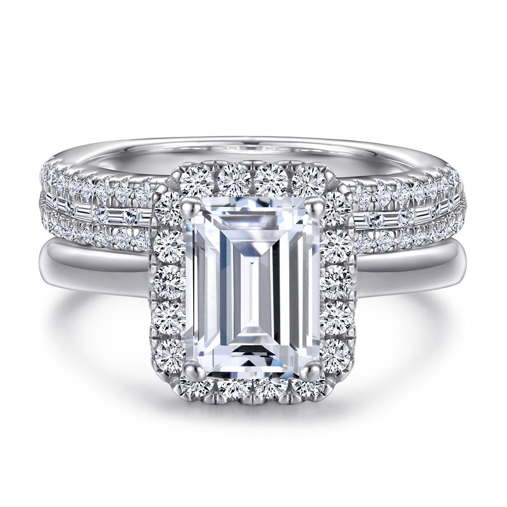 A silver engagement and wedding set that includes a emerald cut halo ring and a matchhing round and emerald cut half eternity ring.