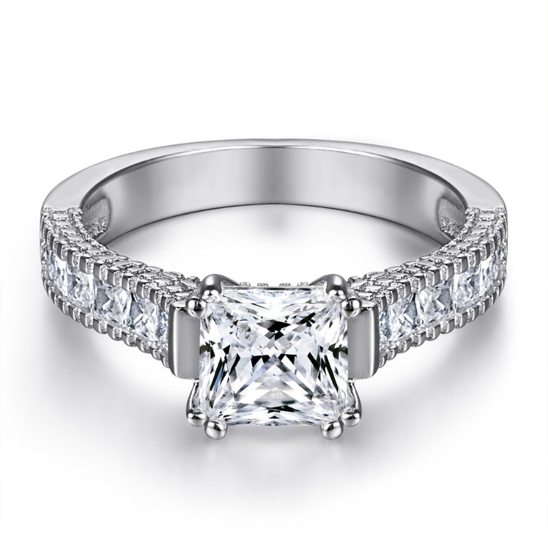 A silver engagement ring set with a princess cut moissanite on a princess cut pave style shank.