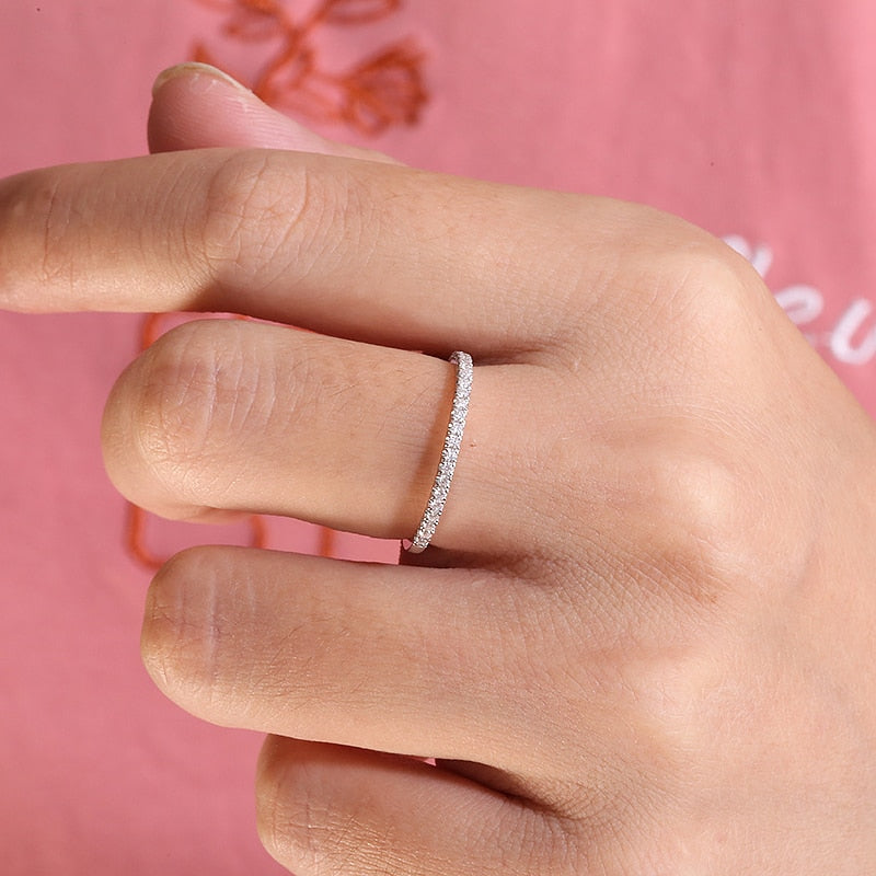 A hand wearing a silver half eternity ring.