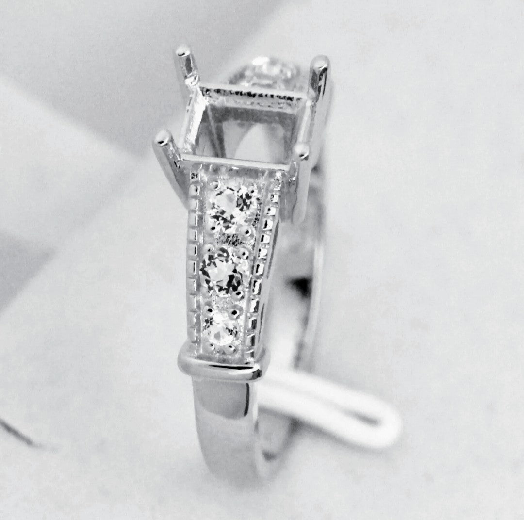A silver semi mount with a pave filigree band made to be set with an emerald cut gem.
