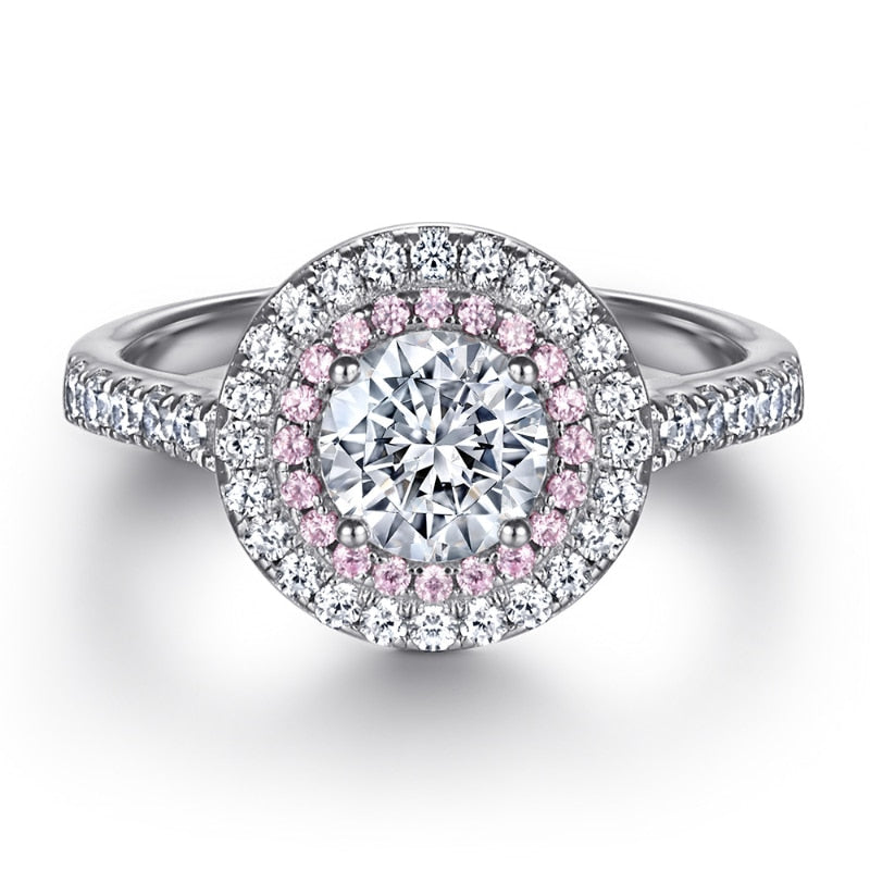 A silver double halo pink and white halo ring set with a round cut moissanite.