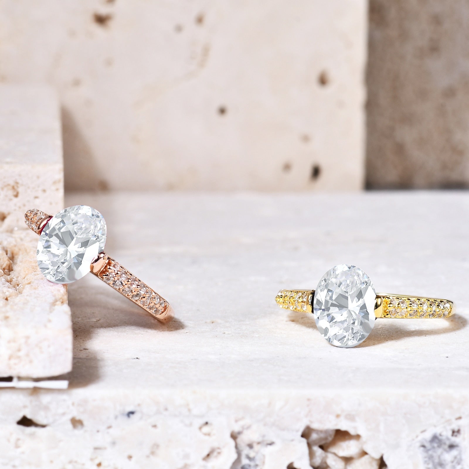 A yellow gold ring and a rose gold ring, tension set with a oval moissanite and double row pave band.