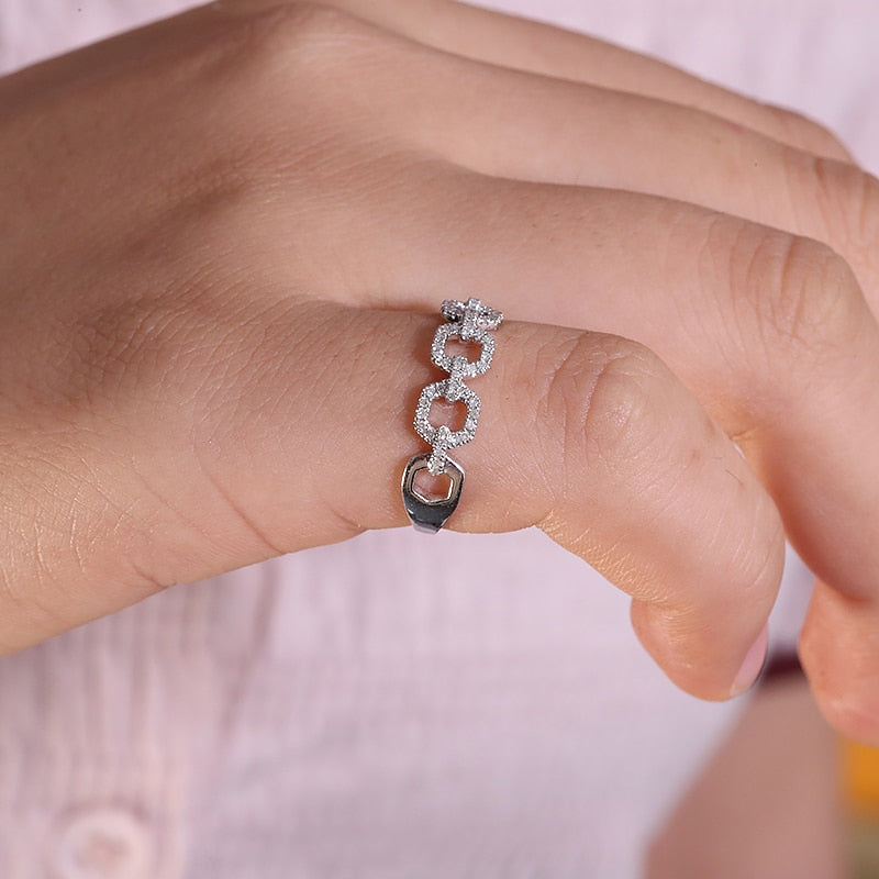 A hand wearing a silver gem encrusted chain link style ring.