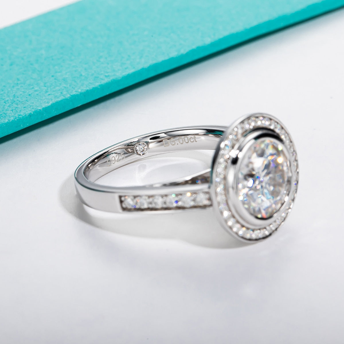 A vintage style ring with 3CT moissanite bezel set surrounded with a halo and pave band.