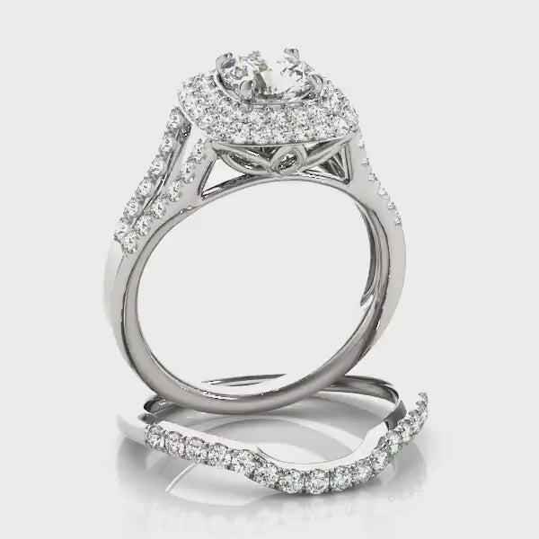 A silver ring set with a round moissanite surrounded by a squared double halo  paired with a matching wedding ring. Both are on a spinning viewing platform.