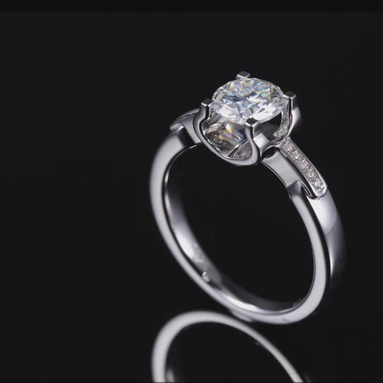 A silver tension set engagement ring with a tapered pave shank on a spinning viewing platform.